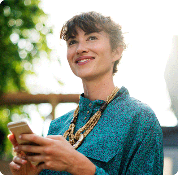 Woman smiling and looking into the distance with her phone in her hand