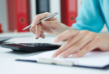 Person sat at a desk with a calculator and notebook