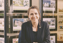 Lady with an estate agency window showing properties in the background
