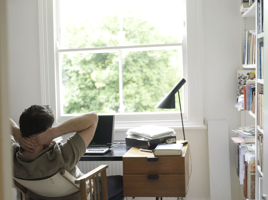 Man sat at his desk with his arms folded behind his head