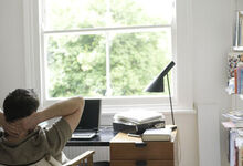 Man sat at his desk with his arms folded behind his head