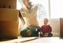 Mum and baby unpacking boxes whilst sat on the floor