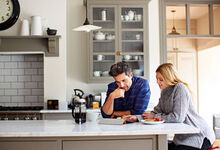 A couple sat in the kitchen looking at paperwork