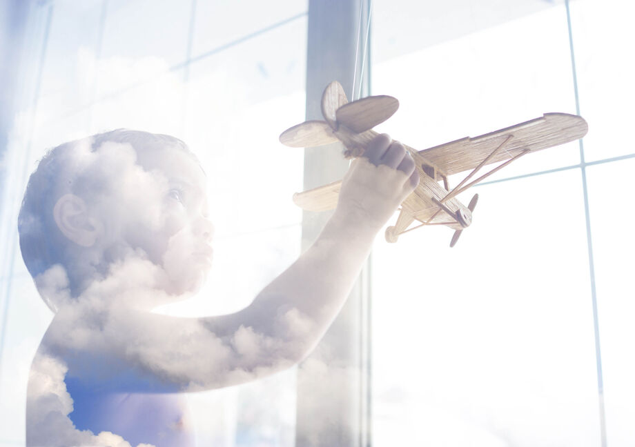 Child with toy aeroplane at the window