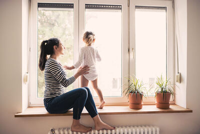 Person holding toddler looking out of the window