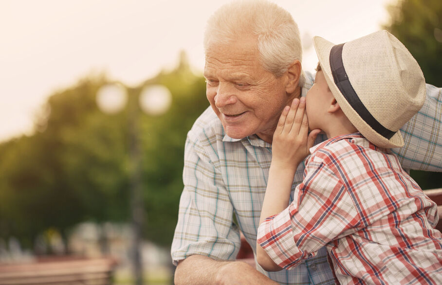 Child speaking into an older persons ear