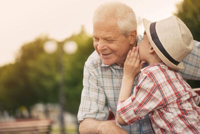 Child speaking into an older persons ear