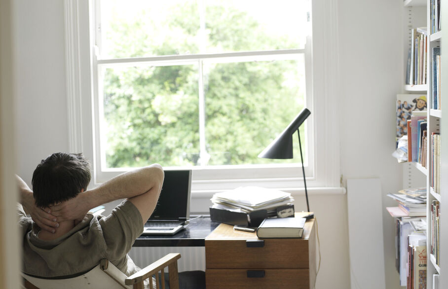 Person sitting back in their chair with their hands behind their head