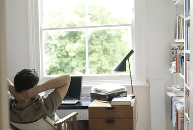 Person sitting back in their chair with their hands behind their head