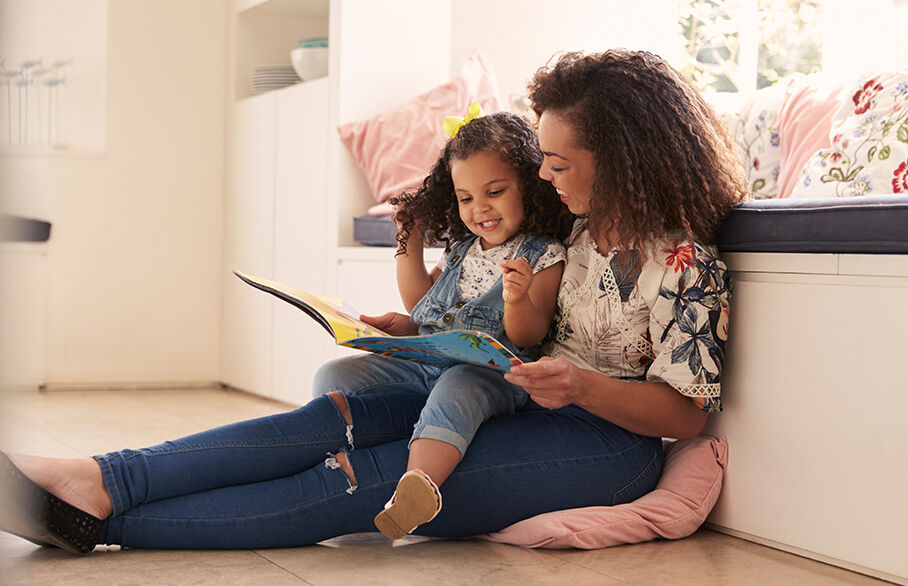 A mother and daughter reading a children's book on the floor