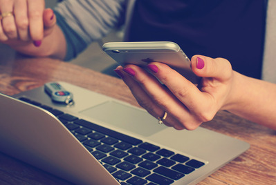 Woman with laptop checking phone