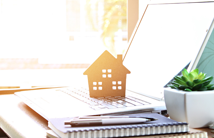 Wooden house cutout on open laptop