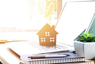 Wooden house cutout on open laptop