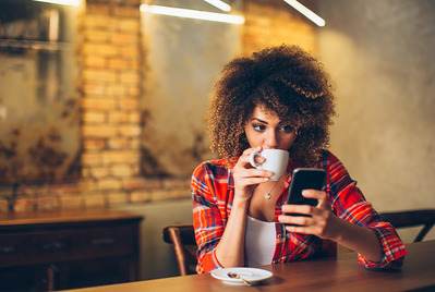 Woman drinking a coffee looking at her phone