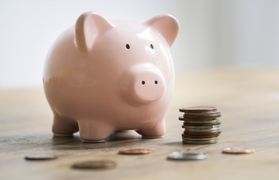 A iggy bank with some coins beside