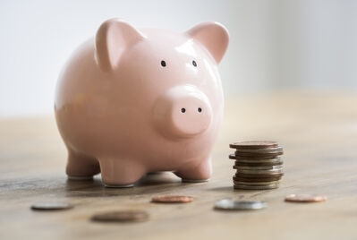A iggy bank with some coins beside