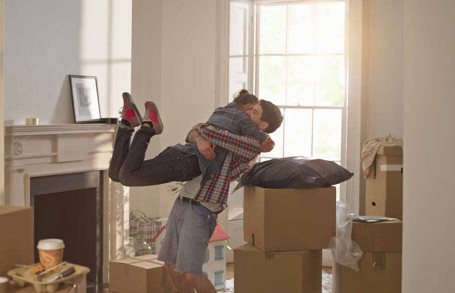 Couple embracing a cuddle surrounded by moving boxes