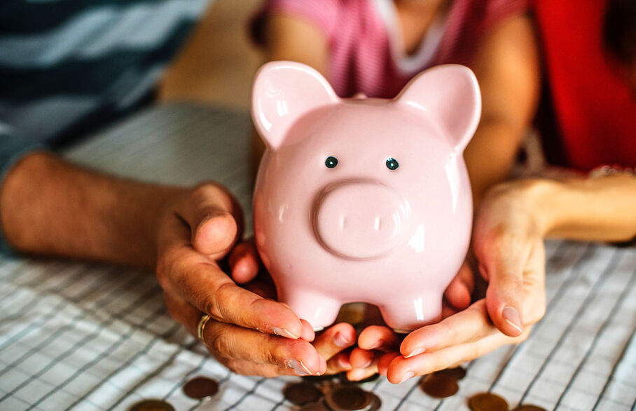 Two people holding a ceramic piggy bank