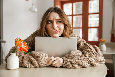 Person sat at a table with chin resting on tablet looking confused