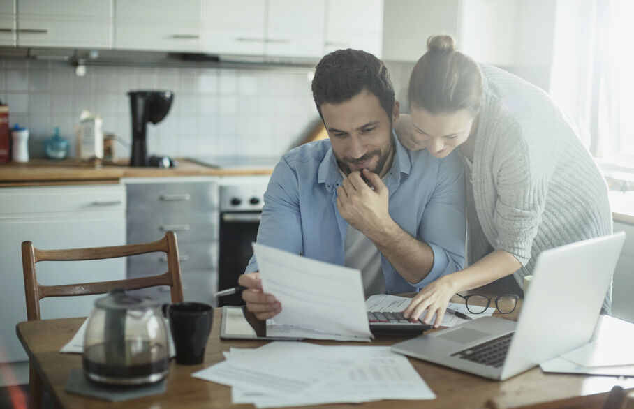Couple looking at documents and a laptop on the table