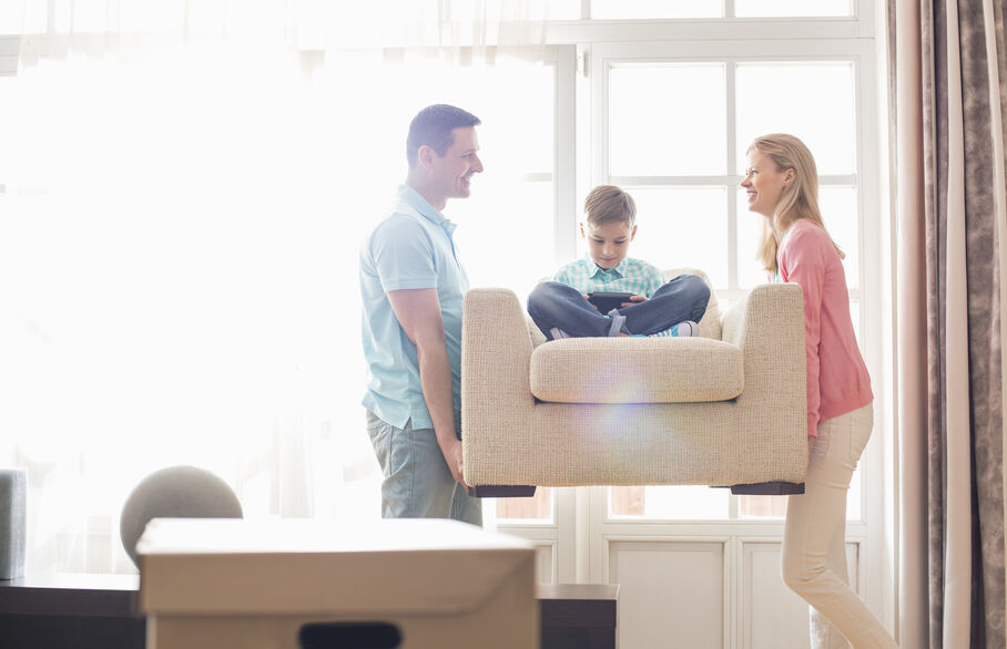 Couple carrying a chair with a chhild sat in it
