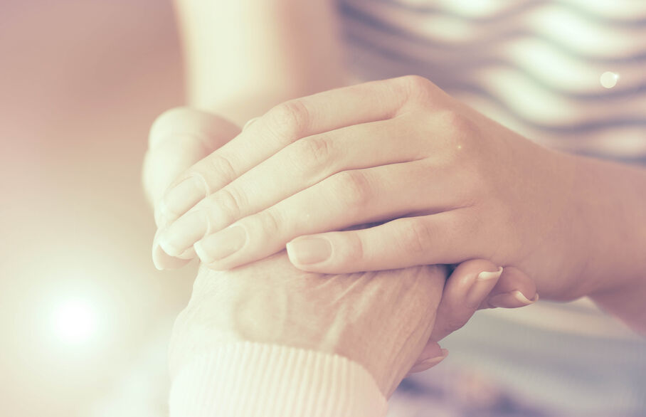 Person holding another persons hand with care