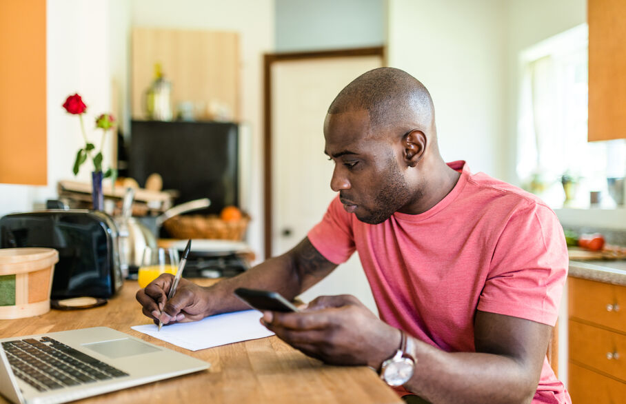 Person looking at a phone and laptop sat at a table