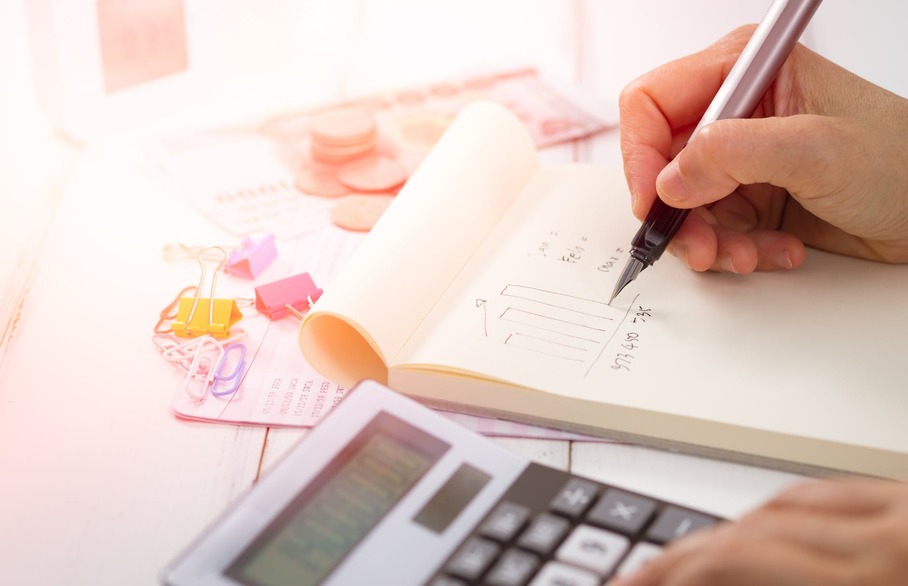 Person writing in a notebook working out calculations