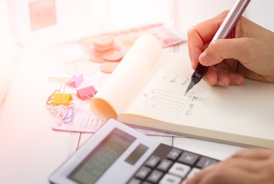 Person writing in a notebook working out calculations