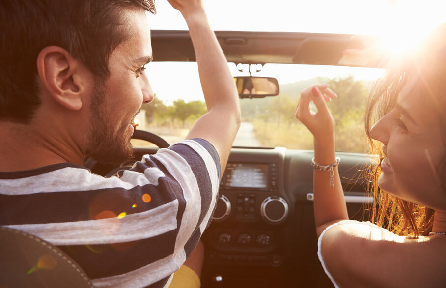 Two people in a car driving into the sunset