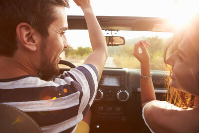 Two people in a car driving into the sunset