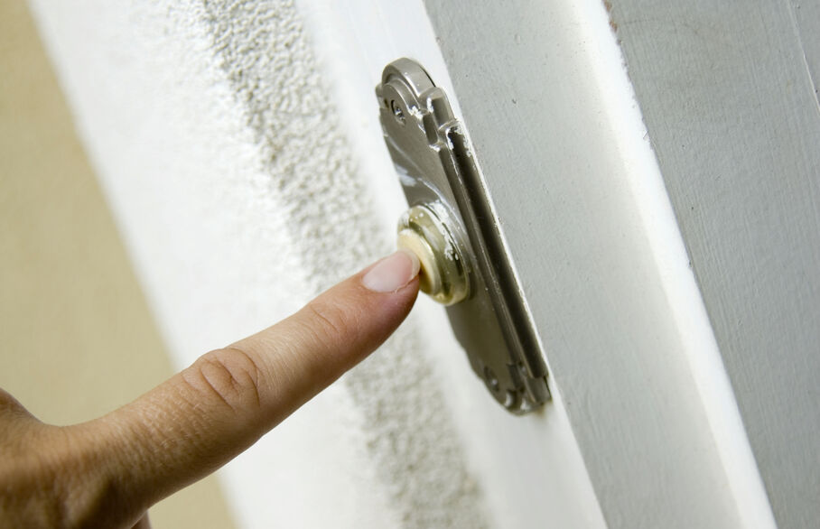 Person's finger pushing a doorbell