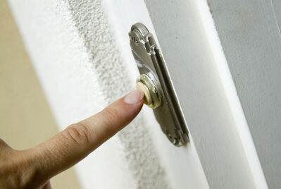 Person's finger pushing a doorbell