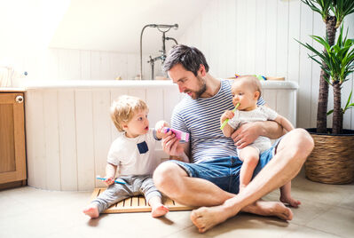 Family of three sat on the floor in the bathroom