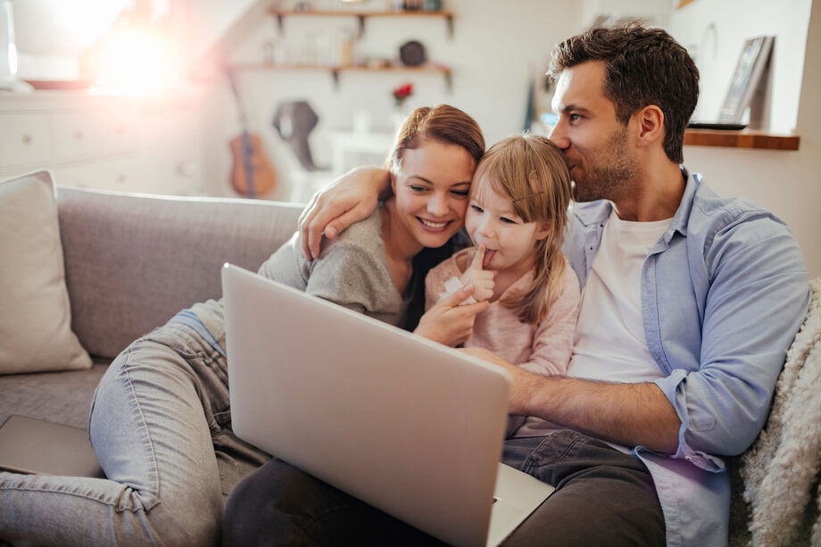 Family cuddled up on the sofa with a laptop