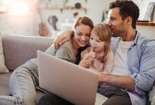 Family cuddled up on the sofa with a laptop