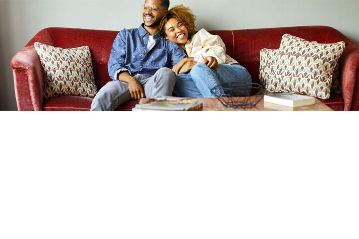 Smiling couple relaxing together on a red sofa