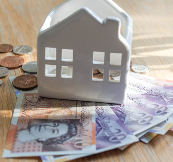 A toy house money bank with British pound notes underneath